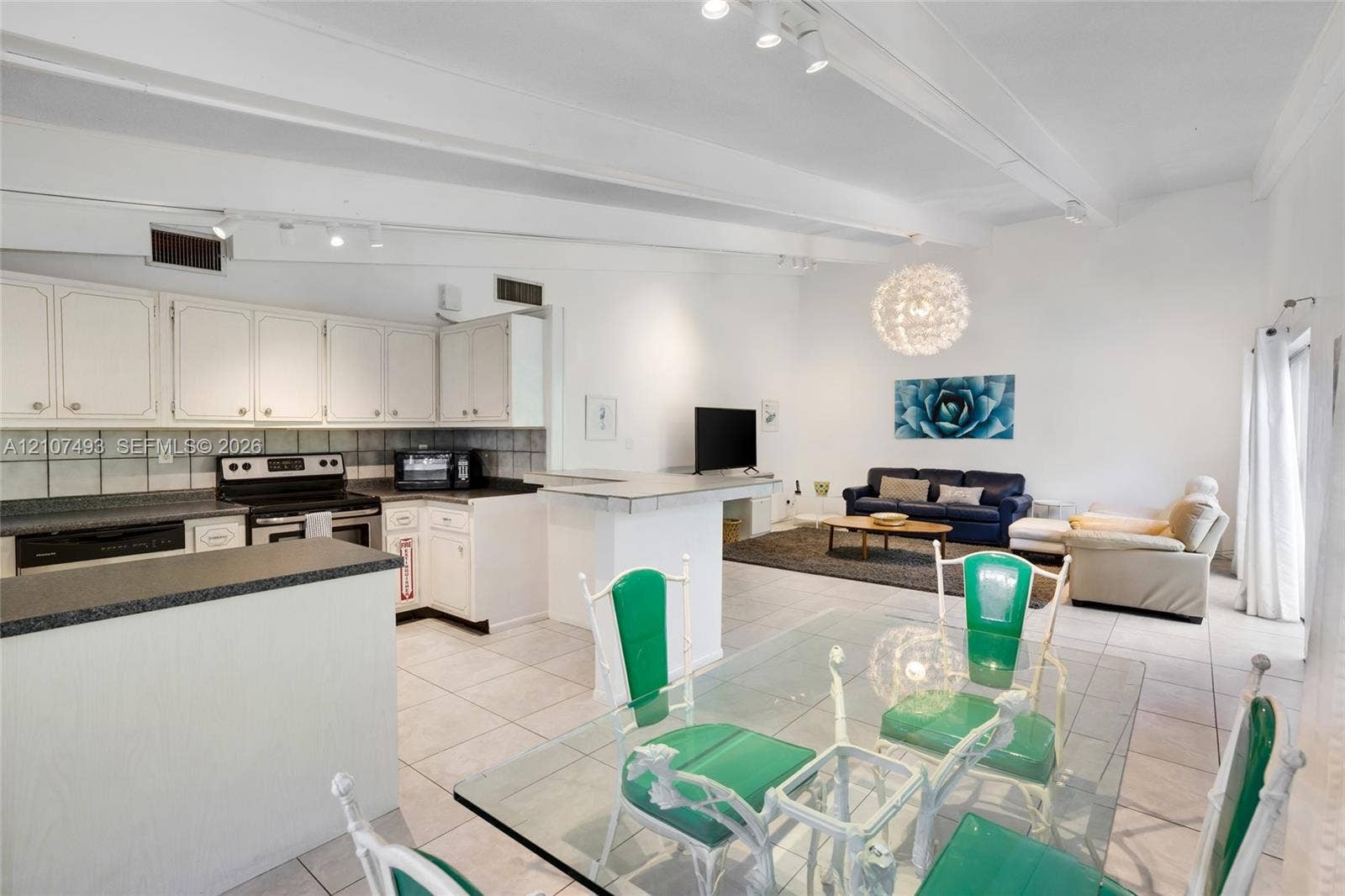 2645 NE 32nd Street, Fort Lauderdale, FL 33306 Open-concept interior featuring vaulted ceilings with exposed beams, ceramic tile flooring, a kitchen peninsula, and recessed lighting