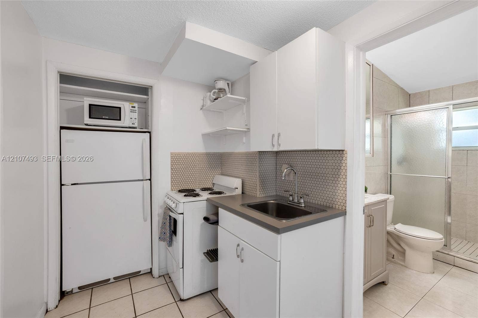 2645 NE 32nd Street, Fort Lauderdale, FL 33306 Kitchen featuring white cabinetry, solid-surface countertop, hexagonal tile backsplash, and ceramic tile flooring