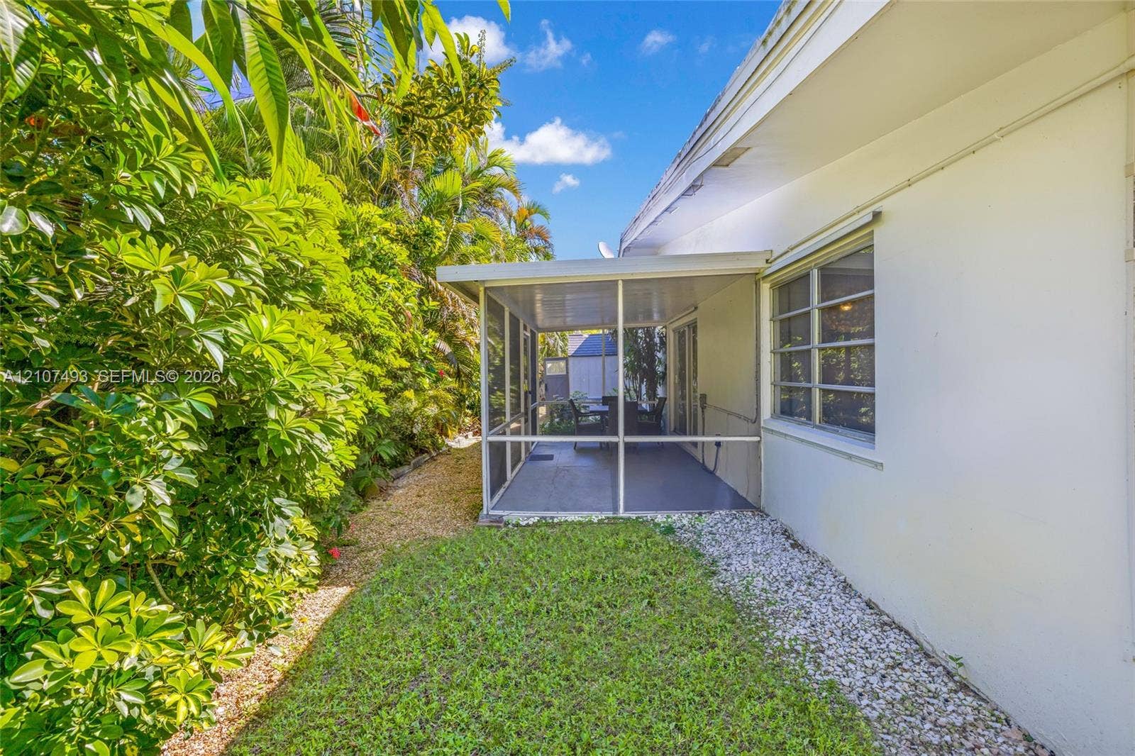 2645 NE 32nd Street, Fort Lauderdale, FL 33306 Screened-in patio with concrete flooring, manicured lawn, established perimeter hedges, and decorative rock landscaping