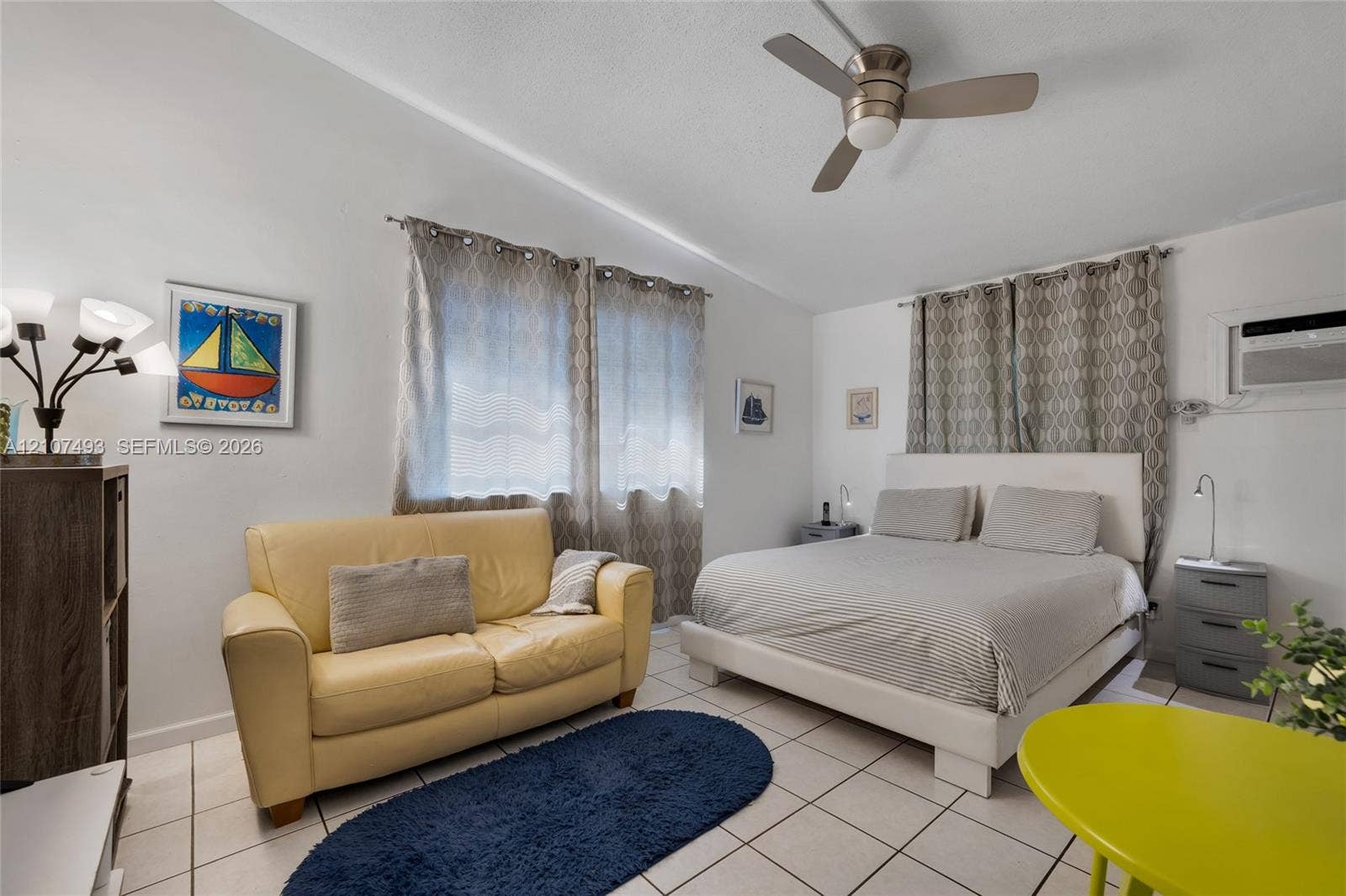 2645 NE 32nd Street, Fort Lauderdale, FL 33306 Neutral-toned interior space featuring light-colored ceramic tile flooring, a brushed metal ceiling fan, and a wall-mounted air conditioning unit