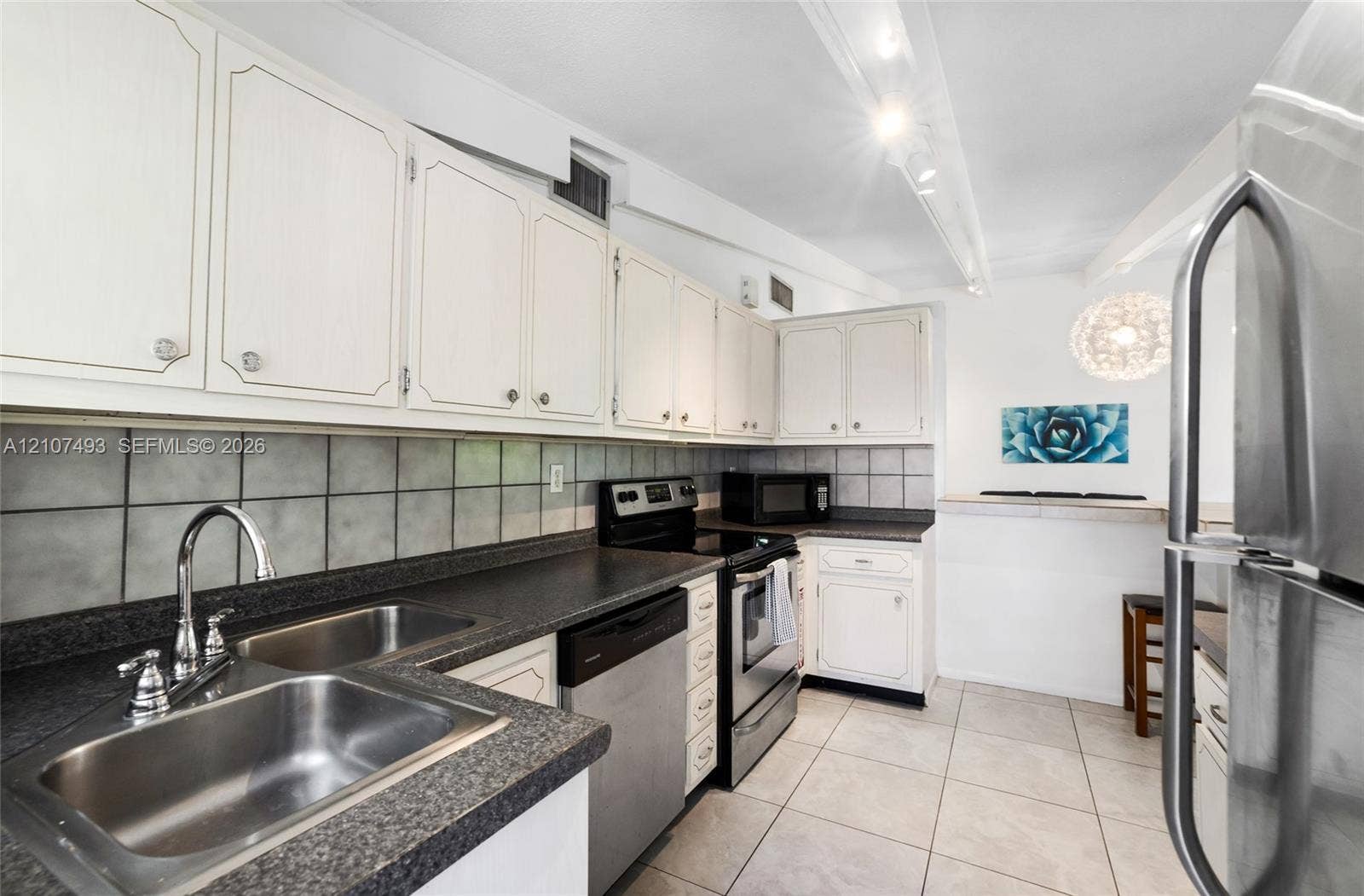 2645 NE 32nd Street, Fort Lauderdale, FL 33306 Kitchen featuring white cabinetry, dark stone-composite countertops, stainless steel appliances, a double-basin stainless steel sink, and ceramic tile flooring