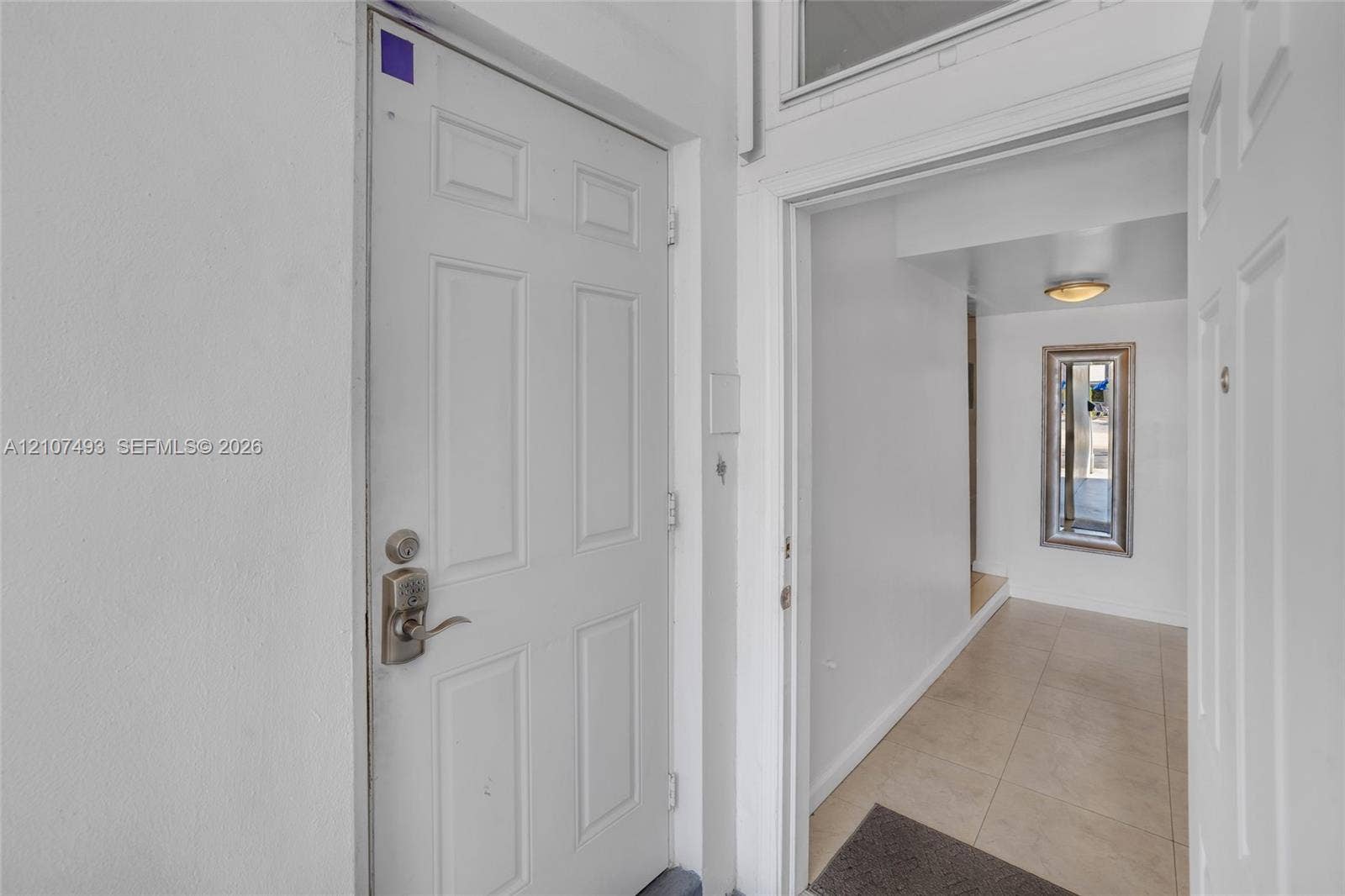 2645 NE 32nd Street, Fort Lauderdale, FL 33306 Six-panel interior door with satin nickel hardware, transom window, and neutral tile flooring