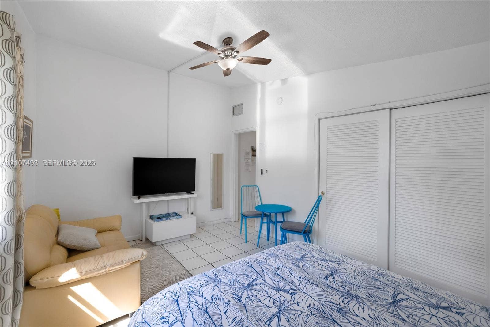 2645 NE 32nd Street, Fort Lauderdale, FL 33306 High ceilings featuring a central ceiling fan with integrated light fixture, ceramic tile flooring, and dual white louvered closet doors