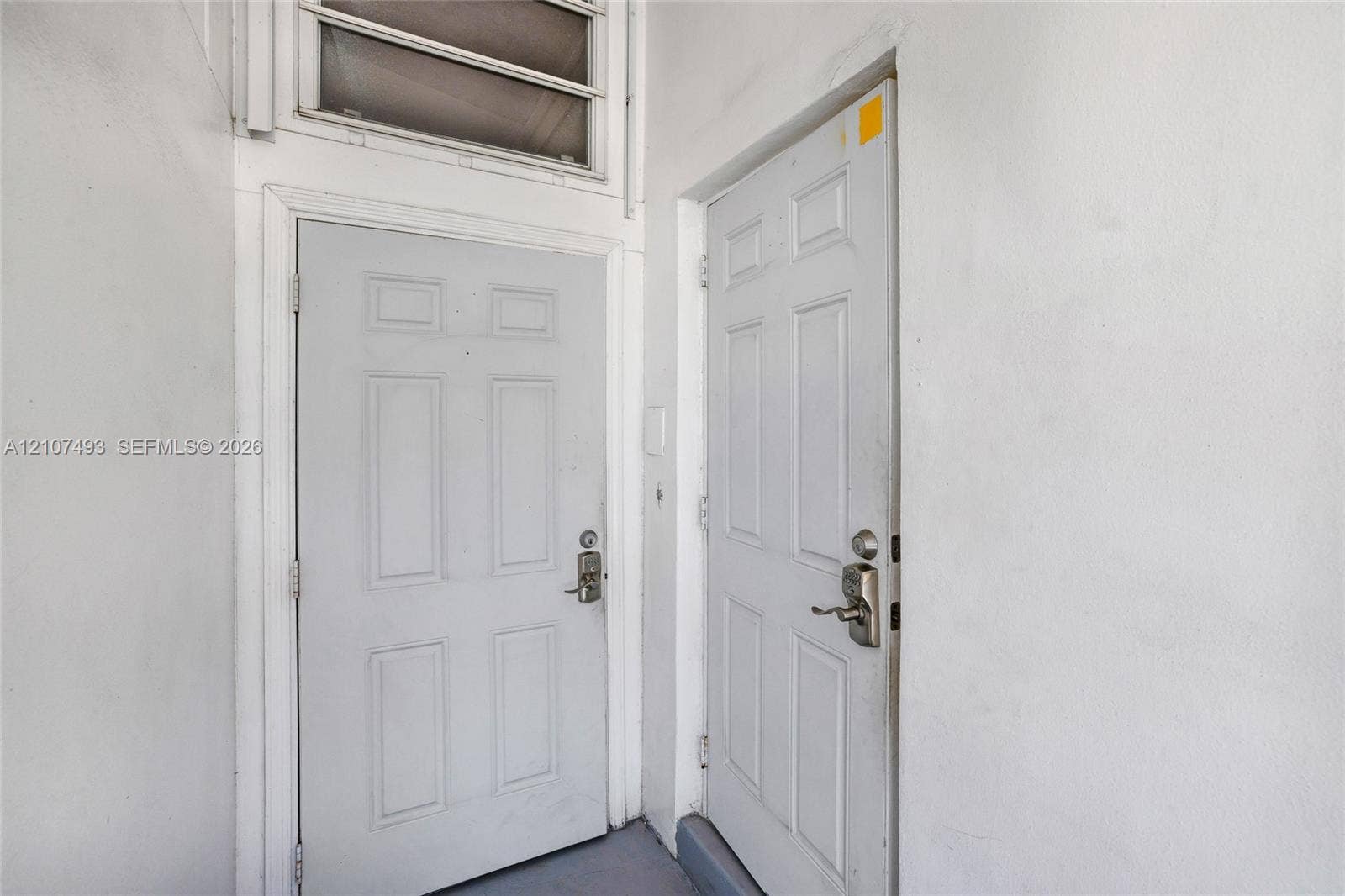 2645 NE 32nd Street, Fort Lauderdale, FL 33306 Two panel-style doors with metallic lever handles, deadbolt locks, and an integrated transom window above the left entrance