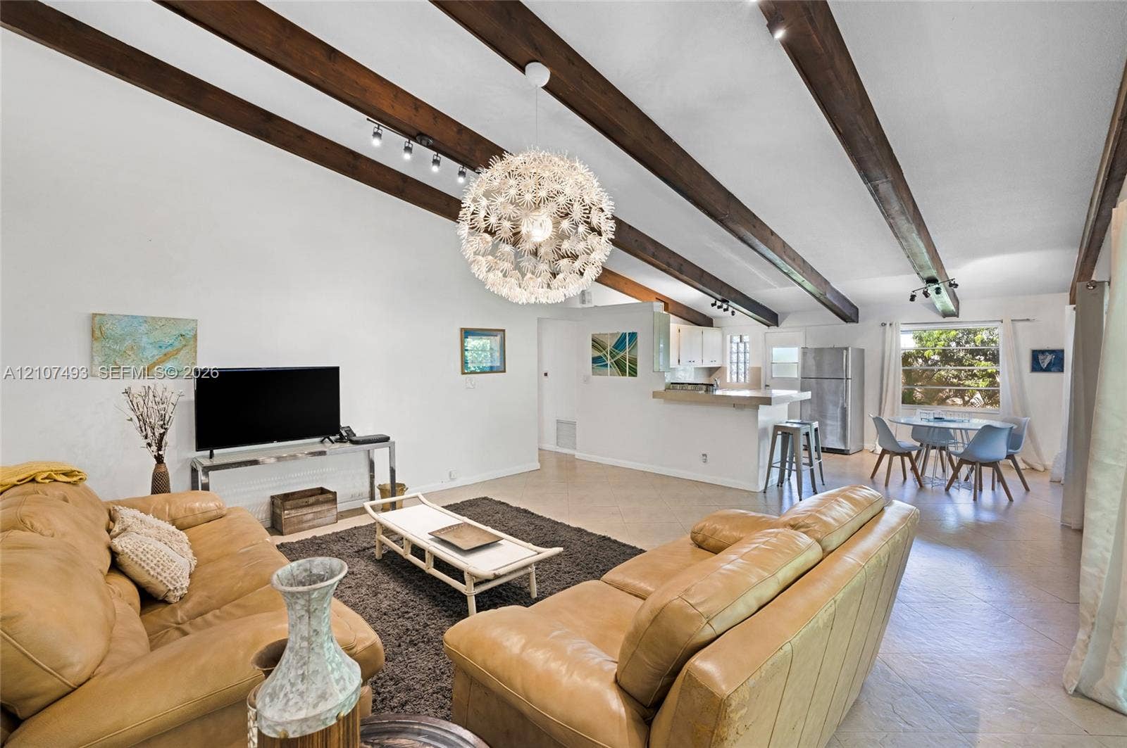 2645 NE 32nd Street, Fort Lauderdale, FL 33306 Vaulted ceilings featuring exposed wood beams, a contemporary sputnik-style chandelier, track lighting, and tile flooring
