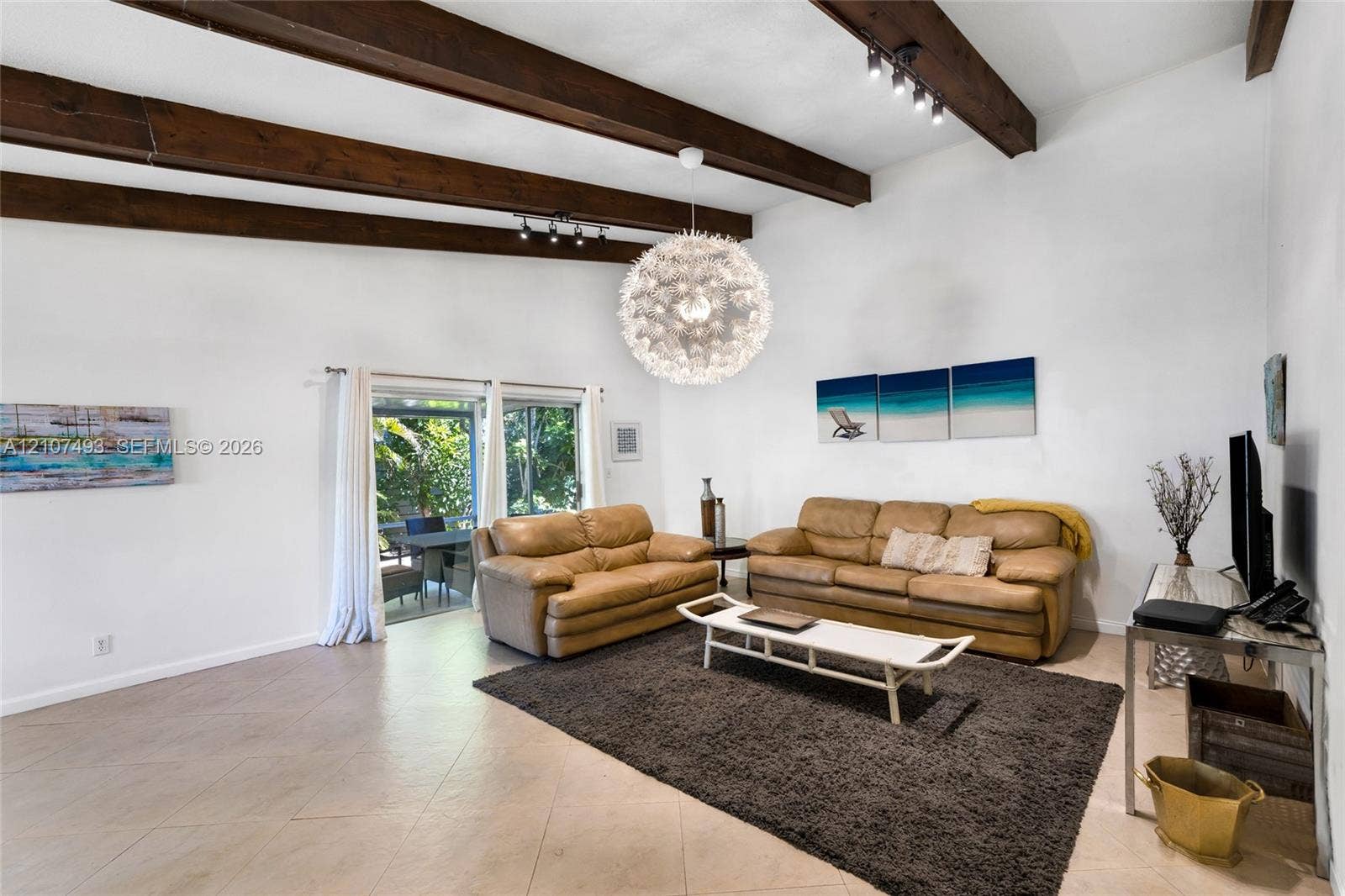 2645 NE 32nd Street, Fort Lauderdale, FL 33306 Vaulted ceilings featuring exposed dark-wood beams, neutral tile flooring, and sliding glass doors