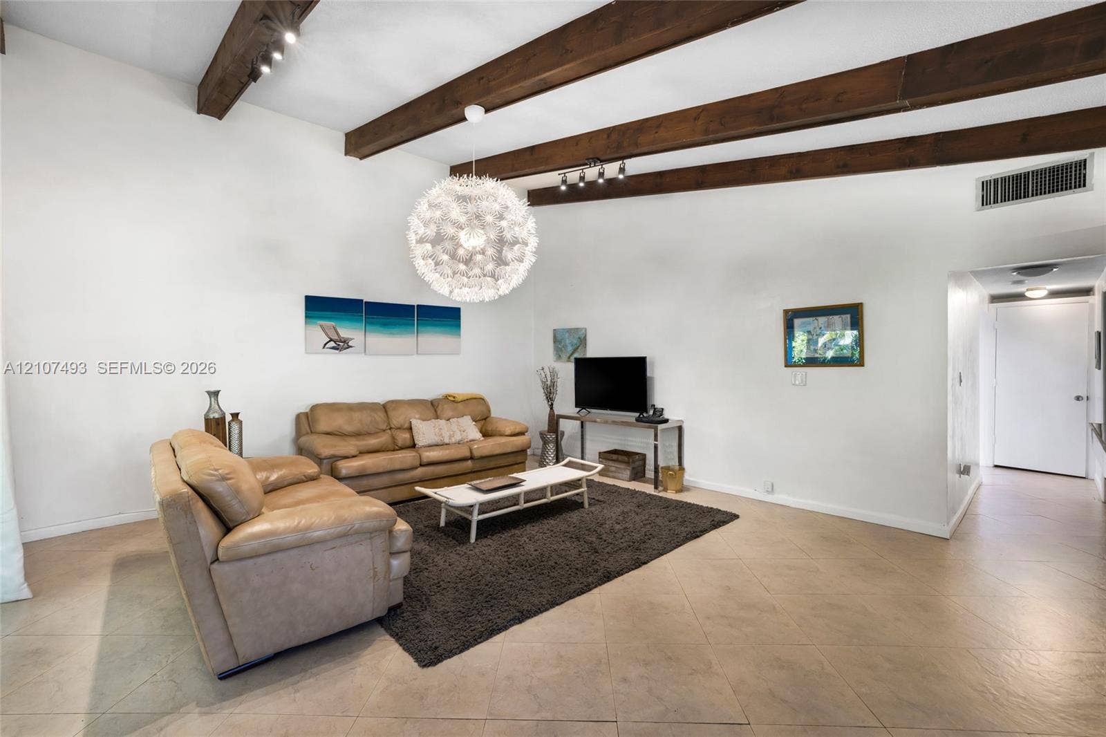 2645 NE 32nd Street, Fort Lauderdale, FL 33306 Vaulted ceiling with exposed wood beams, tile flooring, and a spherical statement pendant light fixture