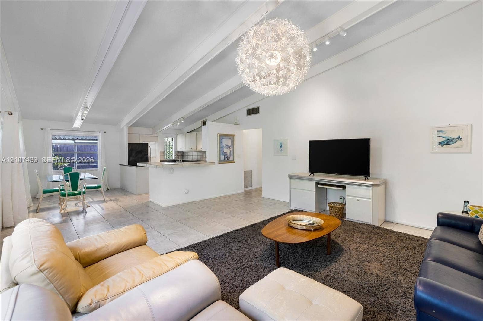 2645 NE 32nd Street, Fort Lauderdale, FL 33306 Vaulted ceilings with exposed structural beams, tile flooring, large spherical pendant light fixture, and built-in cabinetry