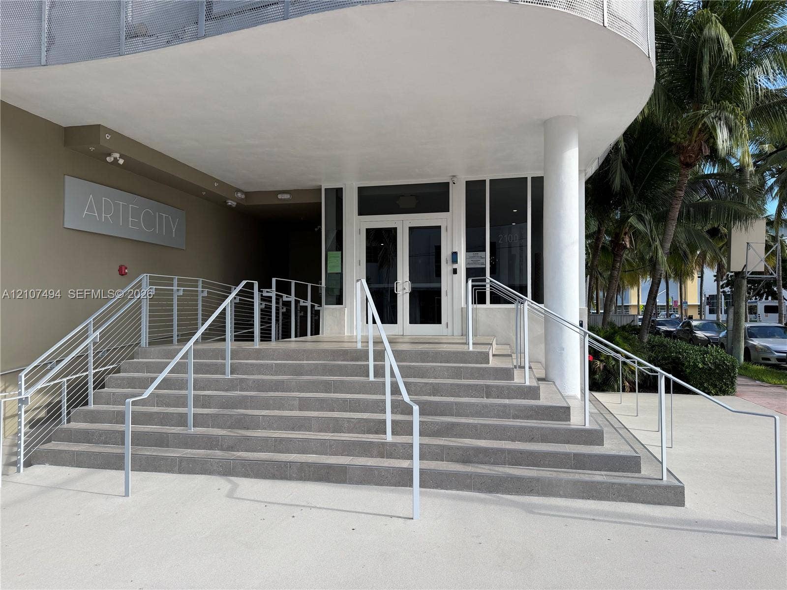 2100 Park Avenue, #305, Miami Beach, Miami Beach, FL 33139 Building entrance featuring a concrete staircase with metal railings, a covered porch, glass-paned double entry doors, and a concrete-paved approach
