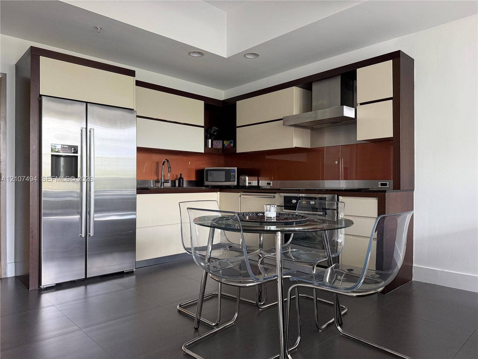 2100 Park Avenue, #305, Miami Beach, Miami Beach, FL 33139 Modern kitchen featuring two-toned cabinetry, stainless steel appliances, a glass-panel backsplash, and dark tile flooring