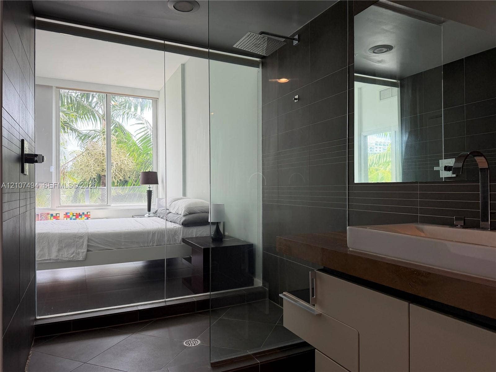 2100 Park Avenue, #305, Miami Beach, Miami Beach, FL 33139 Bathroom featuring large-format dark wall and floor tile, glass-enclosed shower with a rainfall showerhead, and a floating vanity with a vessel sink and contemporary faucet