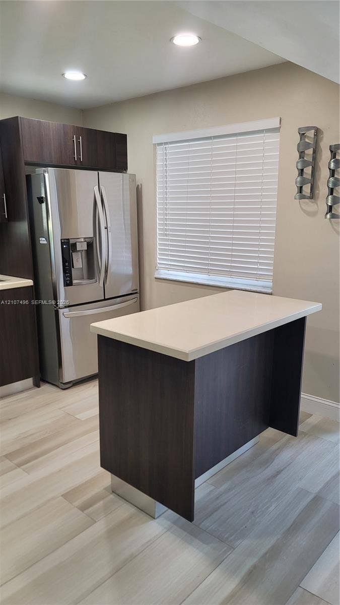 330 Racquet Club Road, #204, Weston, Weston, FL 33326 Kitchen featuring dark wood-finish cabinetry, a central island with a stone-composite countertop, stainless steel refrigerator, recessed lighting, and wood-finish tile flooring