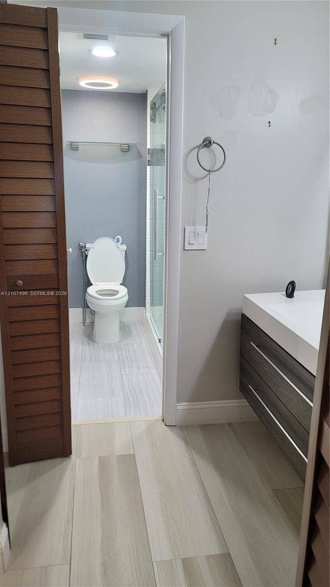 330 Racquet Club Road, #204, Weston, Weston, FL 33326 Modern floating vanity with a white countertop, wood-finish cabinetry, louvered closet doors, and large-format tile flooring