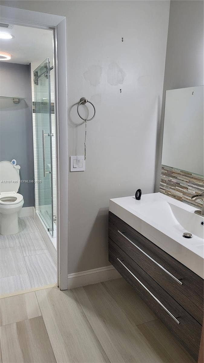 330 Racquet Club Road, #204, Weston, Weston, FL 33326 Floating vanity with dual soft-close drawers, integrated white basin, stacked stone backsplash, and wood-finish flooring