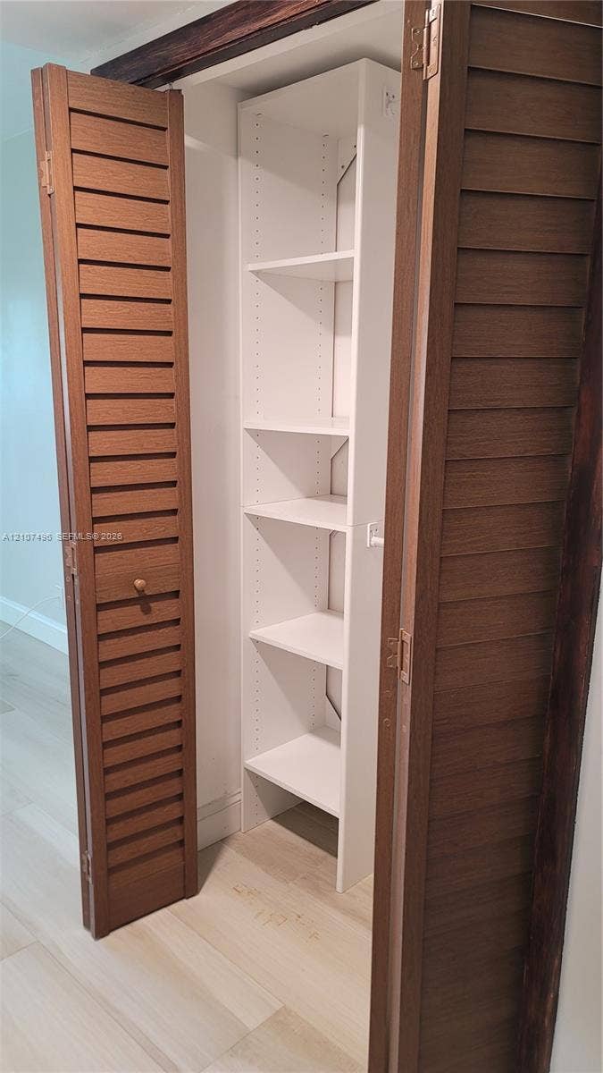 330 Racquet Club Road, #204, Weston, Weston, FL 33326 Storage closet featuring wood-finish louvered bi-fold doors and white custom built-in shelving