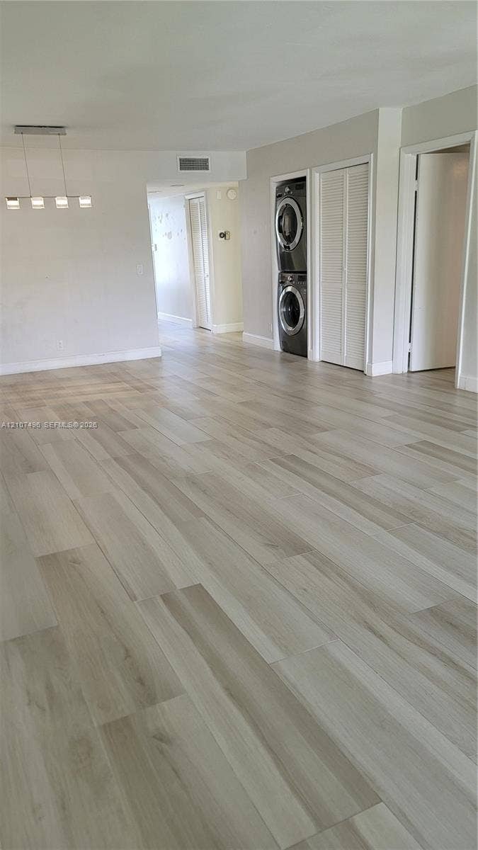 330 Racquet Club Road, #204, Weston, Weston, FL 33326 Open-concept area featuring light-toned wood-finish flooring, recessed lighting, multi-pendant light fixture, and built-in stackable laundry unit with louvered closet doors