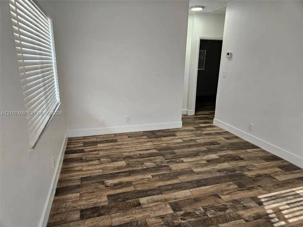 730 SW 4th Street, #A, Dania, Dania Beach, FL 33004 Interior space featuring wood-finish flooring, white walls, and a window equipped with horizontal blinds