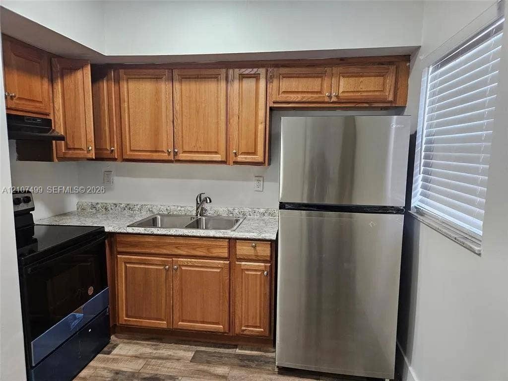 730 SW 4th Street, #A, Dania, Dania Beach, FL 33004 Kitchen featuring wood cabinetry, stone-finish countertops, stainless steel refrigerator, dual-basin sink, and wood-finish flooring