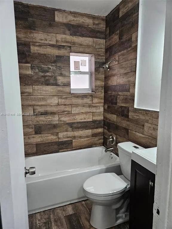 730 SW 4th Street, #A, Dania, Dania Beach, FL 33004 Bathroom featuring wood-finish wall tiling, white porcelain bathtub, wall-mounted showerhead, and dark cabinetry with an integrated basin