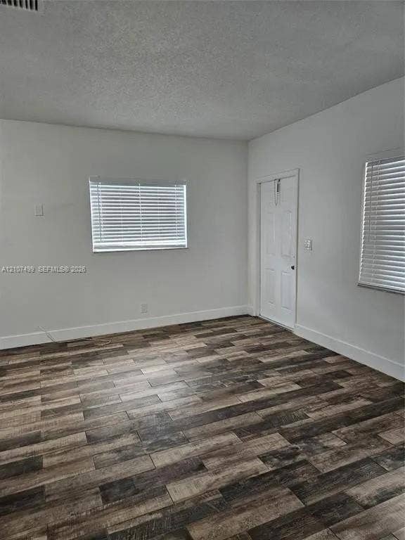 730 SW 4th Street, #A, Dania, Dania Beach, FL 33004 Interior room featuring wood-finish flooring, white walls, and two windows equipped with horizontal blinds