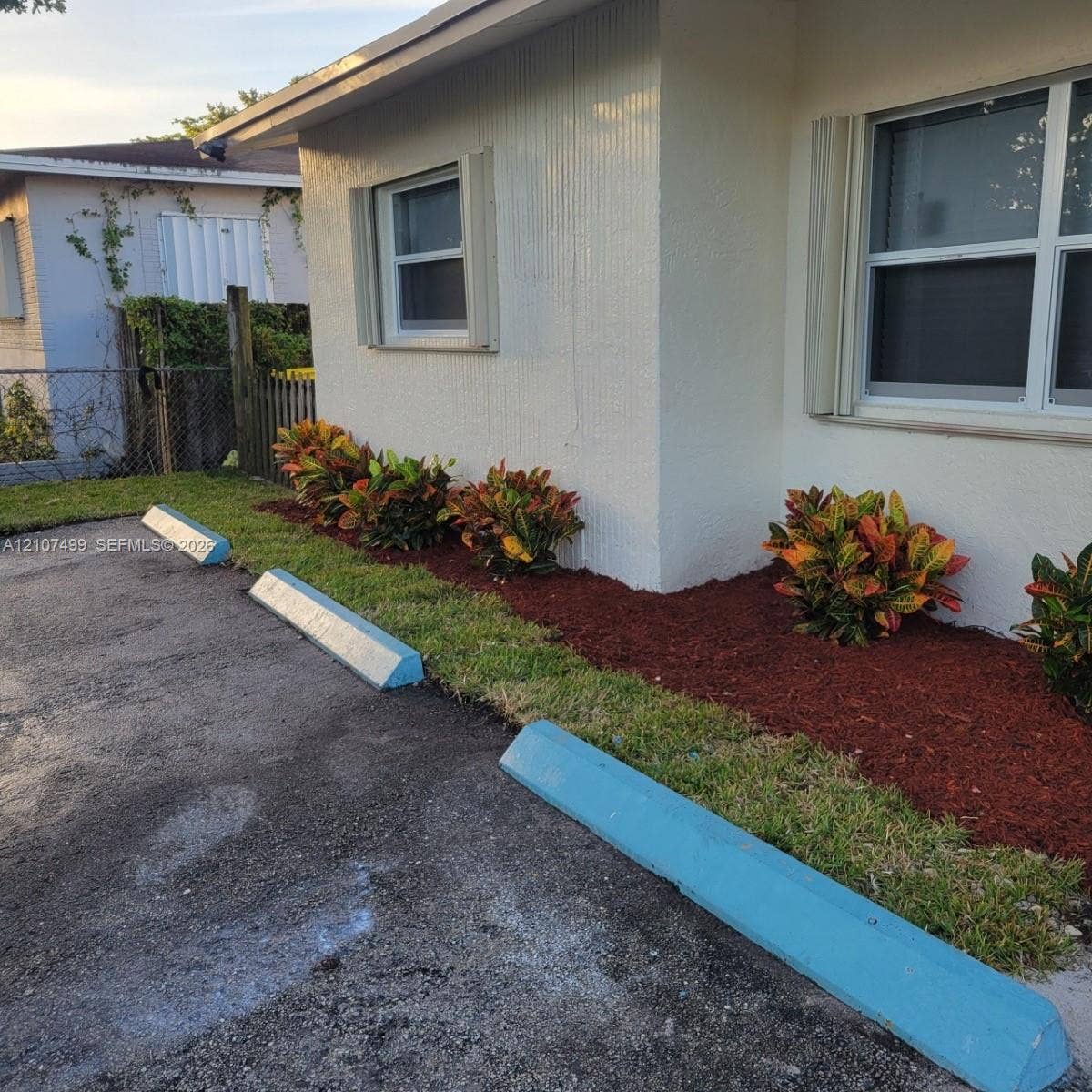 730 SW 4th Street, #A, Dania, Dania Beach, FL 33004 Exterior facade featuring stucco siding, multi-pane windows, paved parking area with concrete wheel stops, and landscaped garden beds with decorative mulch