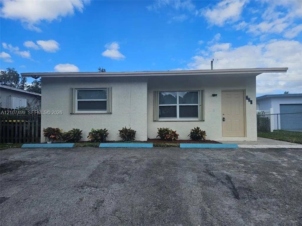 730 SW 4th Street, #A, Dania, Dania Beach, FL 33004 Single-story exterior featuring a light-toned masonry facade, overhanging roofline, horizontal sliding windows with trim, and concrete parking area