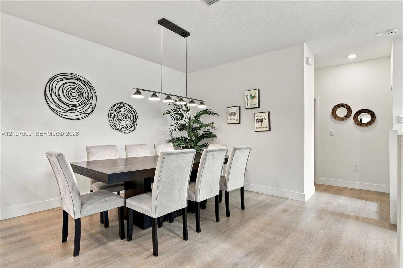 Neutral wall color palette, light-toned wood-finish flooring, and a linear multi-light pendant fixture