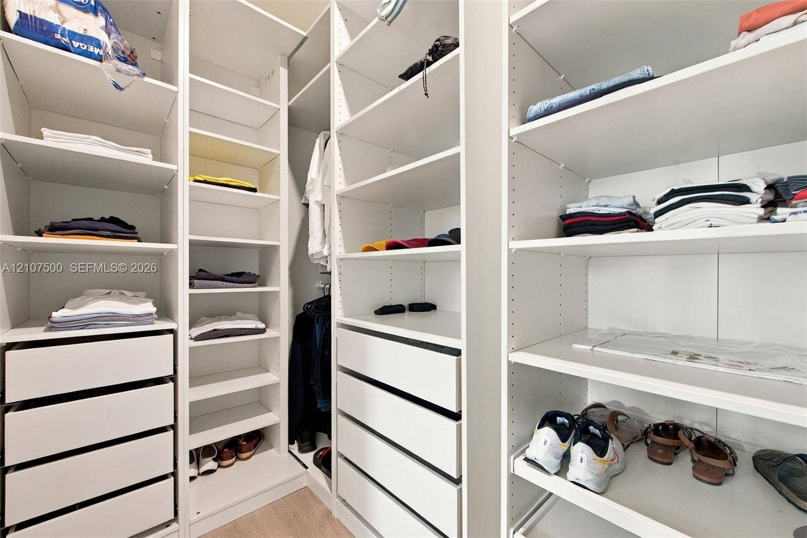 Custom closet system featuring white built-in shelving, adjustable storage racks, integrated cabinetry, and multi-tier drawer units
