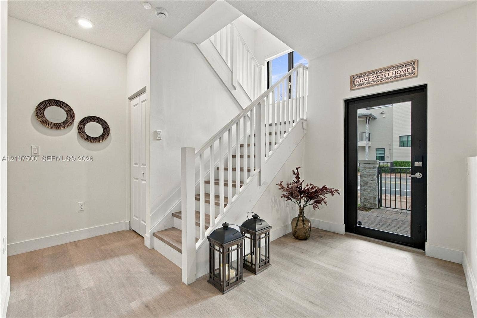 Foyer featuring wood-finish flooring, a glass-panel entry door, and a staircase with white painted balusters and wood-finish treads