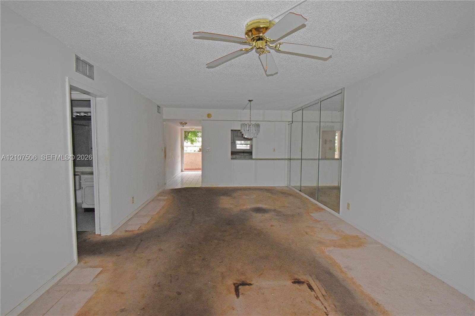 830 S Hollybrook Drive, #207, Pembroke Pines, FL 33025 Interior space featuring full-wall mirrored closet doors, a ceiling-mounted fan, a crystal-style chandelier, and a pass-through opening