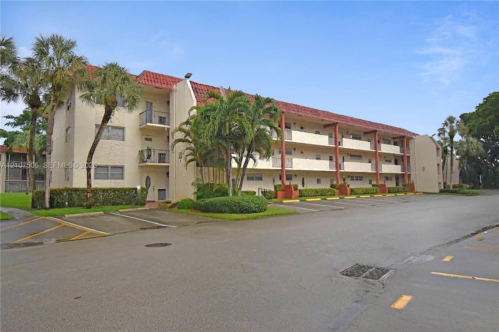 830 S Hollybrook Drive, #207, Pembroke Pines, FL 33025 Multi-level exterior featuring a stucco facade, red tile roofing, private balcony spaces, and mature palm trees