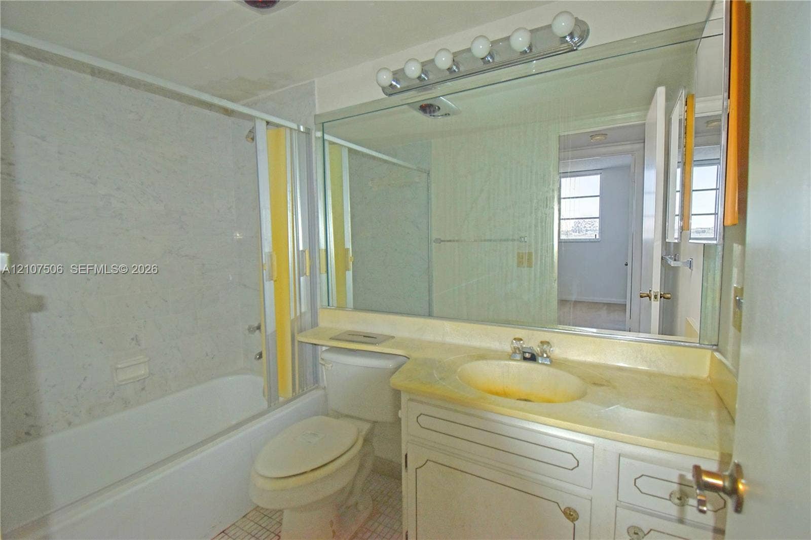 830 S Hollybrook Drive, #207, Pembroke Pines, FL 33025 Full-width vanity with integrated countertop and sink, large wall-mounted mirror, overhead five-bulb vanity light, and tub-shower combination with surround