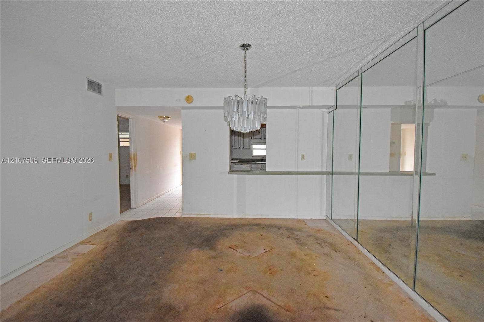 830 S Hollybrook Drive, #207, Pembroke Pines, FL 33025 Interior space featuring a pass-through opening, a suspended multi-tiered chandelier, and a wall of floor-to-ceiling mirrored panels