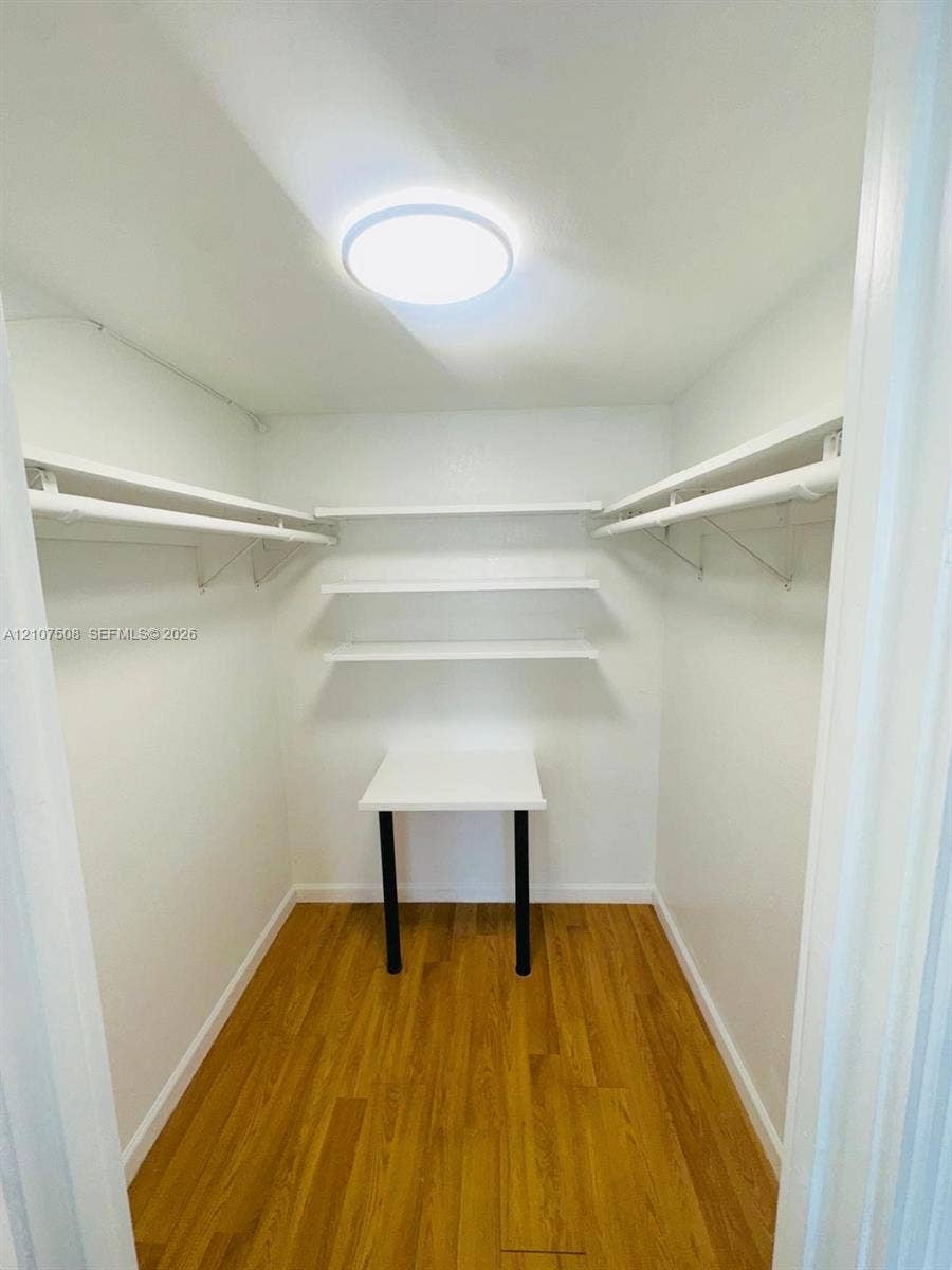 1020 Meridian Avenue, #415, Miami Beach, Miami Beach, FL 33139 Walk-in closet featuring wood-finish flooring, built-in shelving, integrated clothing rods, a fixed wall-mounted desk, and flush-mount ceiling lighting