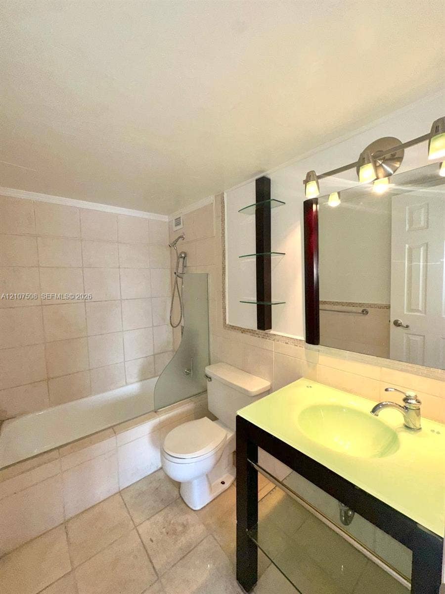 1020 Meridian Avenue, #415, Miami Beach, Miami Beach, FL 33139 Bathroom featuring a pedestal vanity with a glass countertop, integrated sink, and tiered glass shelving, complemented by a tiled shower surround with a fixed glass splash panel and multi-light vanity fixture