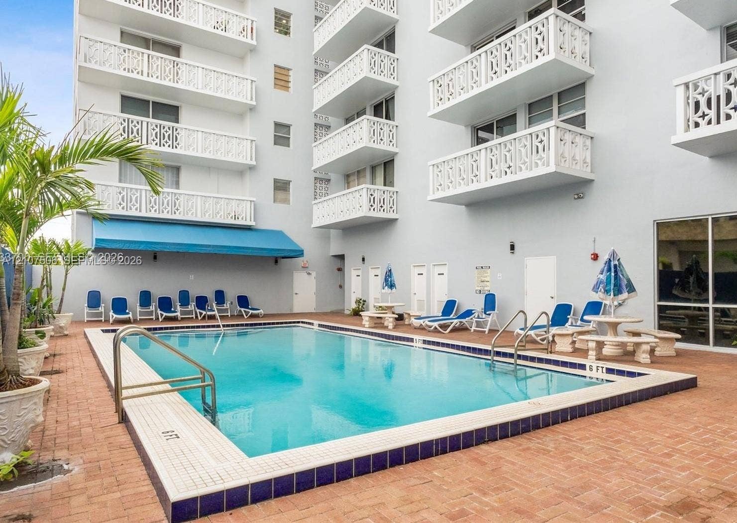 1020 Meridian Avenue, #415, Miami Beach, Miami Beach, FL 33139 Swimming pool featuring a brick-paver deck, decorative metal balcony railings, and a blue retractable awning