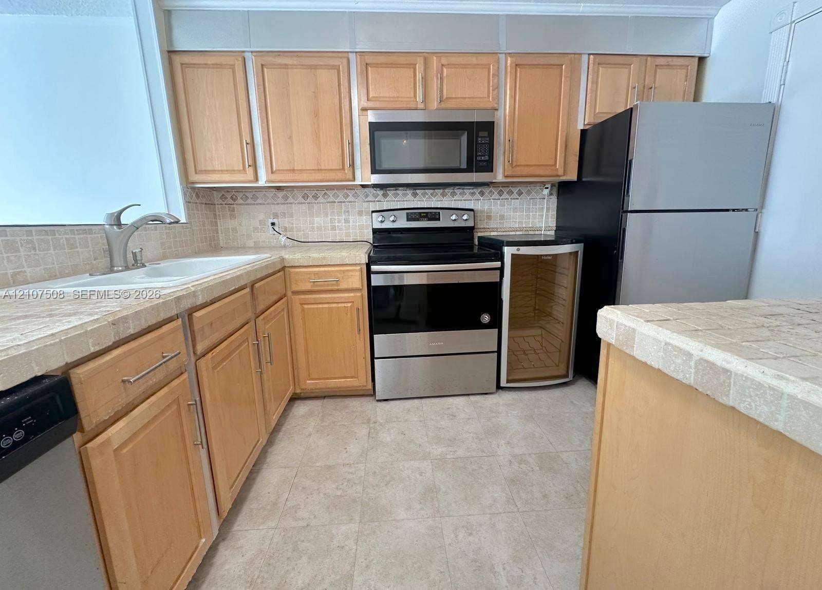 1020 Meridian Avenue, #415, Miami Beach, Miami Beach, FL 33139 Kitchen featuring wood cabinetry, stone-finish tile countertops, mosaic tile backsplash, stainless steel appliances, and integrated wine cooler