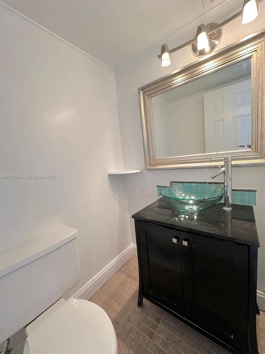 1020 Meridian Avenue, #415, Miami Beach, Miami Beach, FL 33139 Black vanity cabinet with a stone countertop, circular glass vessel sink, chrome high-arc faucet, and a decorative tile backsplash