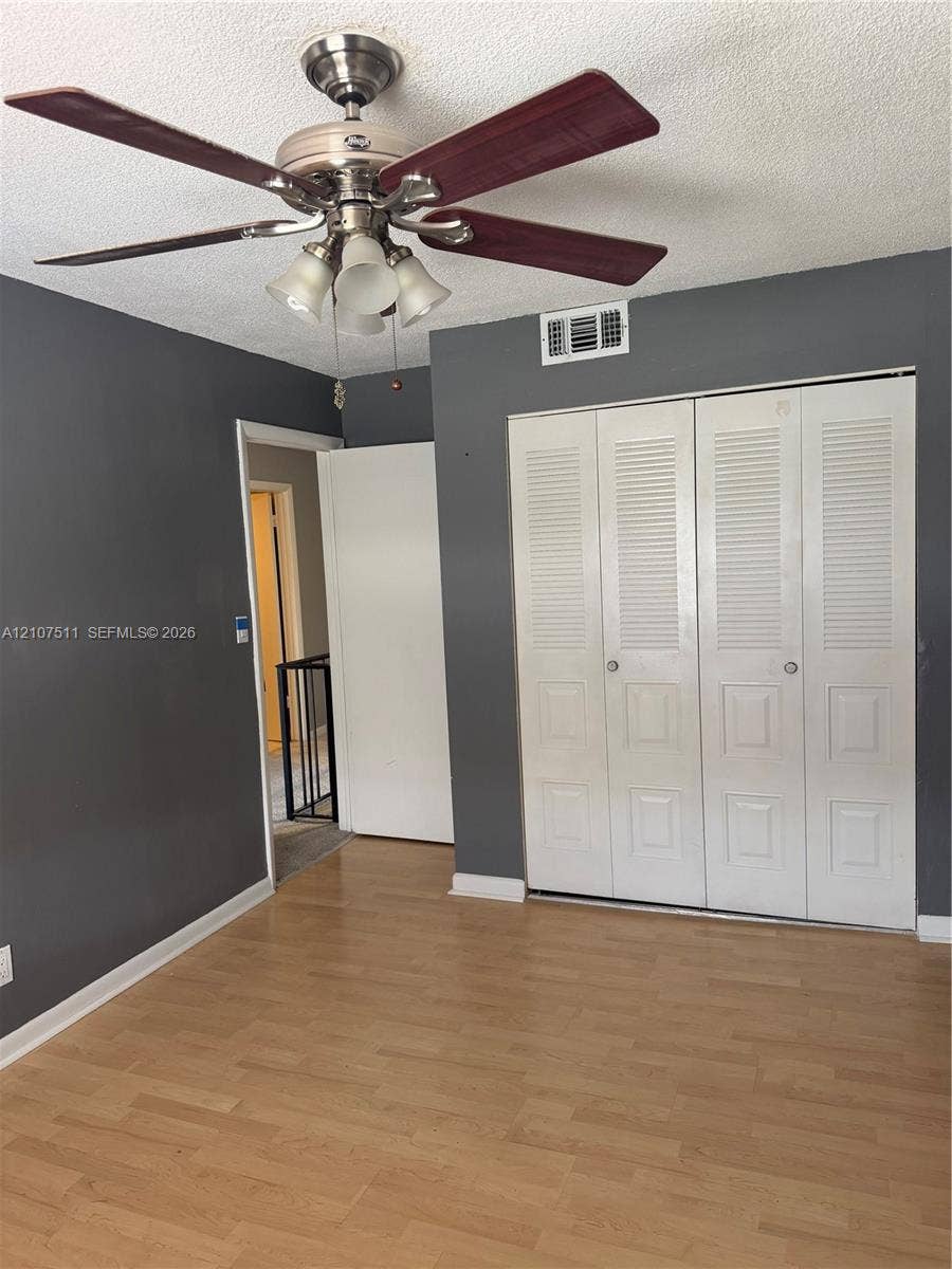 12 S Valencia Drive, #5-4, Davie, FL 33324 Wood-finish flooring, neutral-toned walls, ceiling fan with integrated lighting, and white louvered-panel closet doors
