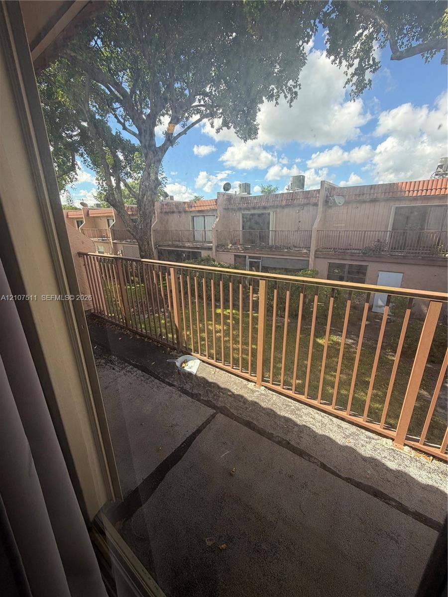 12 S Valencia Drive, #5-4, Davie, FL 33324 Second-story exterior balcony featuring metal railings, concrete flooring, and mature tree canopy
