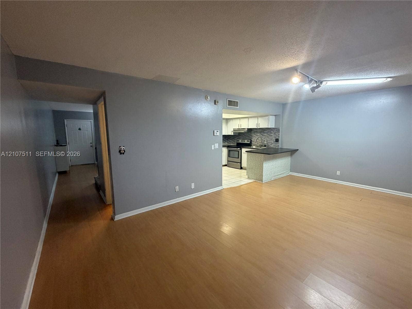 12 S Valencia Drive, #5-4, Davie, FL 33324 Open-concept interior featuring light wood-finish flooring, a kitchen breakfast bar with stone-finish base, tile flooring in the kitchen area, and track lighting