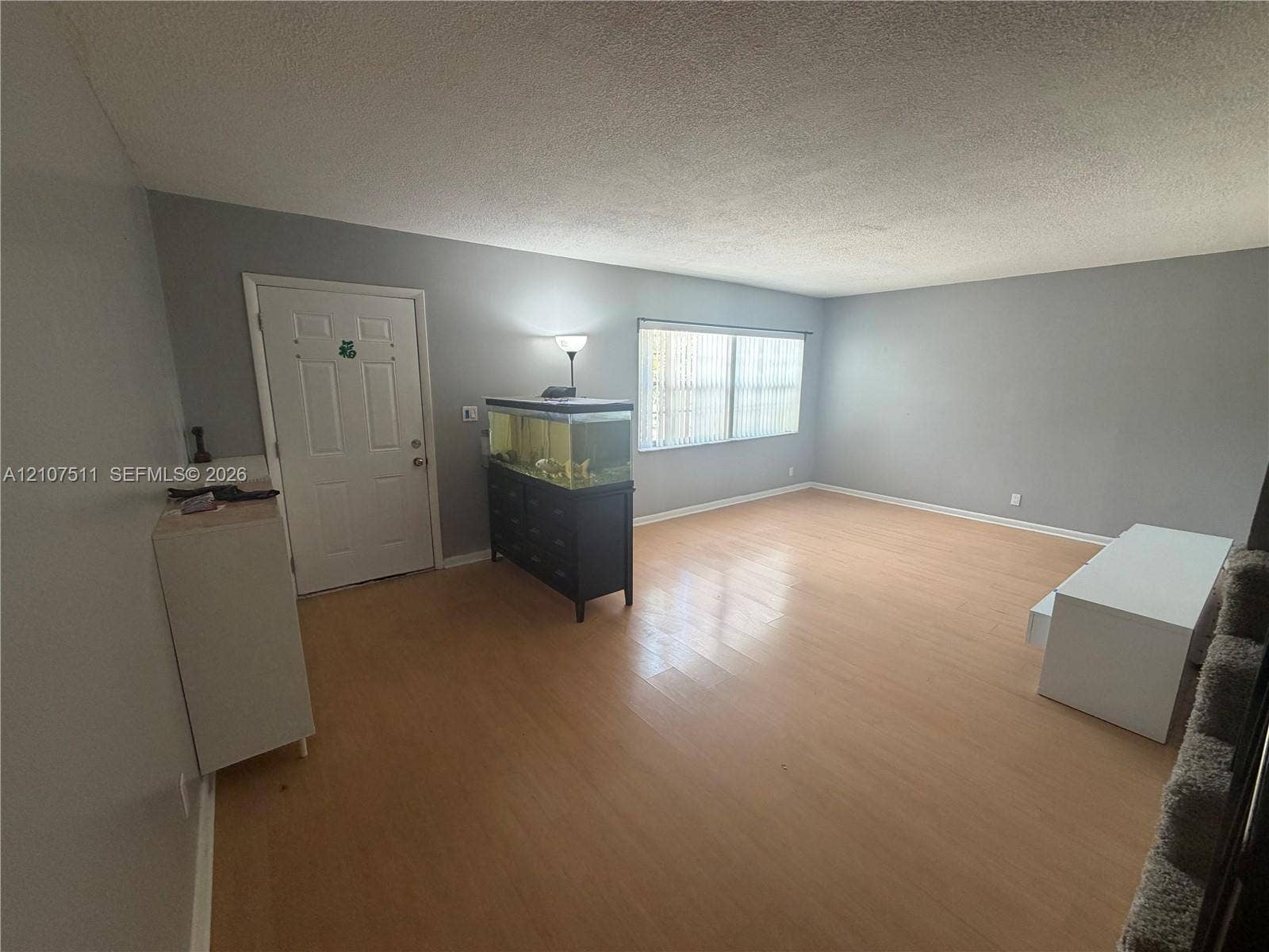 12 S Valencia Drive, #5-4, Davie, FL 33324 Neutral-toned interior featuring wood-finish flooring, a six-panel entry door, and a horizontal window with vertical blinds