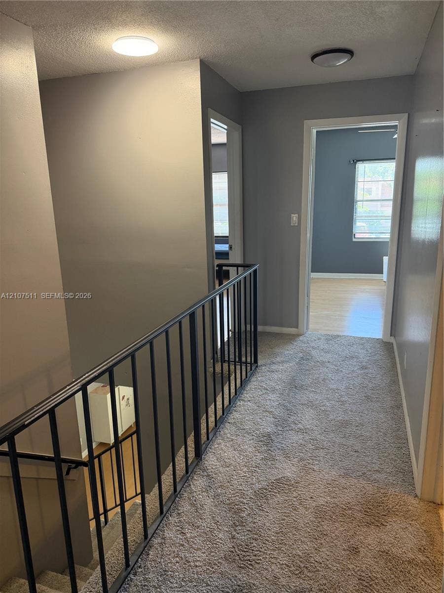 12 S Valencia Drive, #5-4, Davie, FL 33324 Hallway featuring wall-to-wall carpeting, neutral interior paint, and a black metal handrail