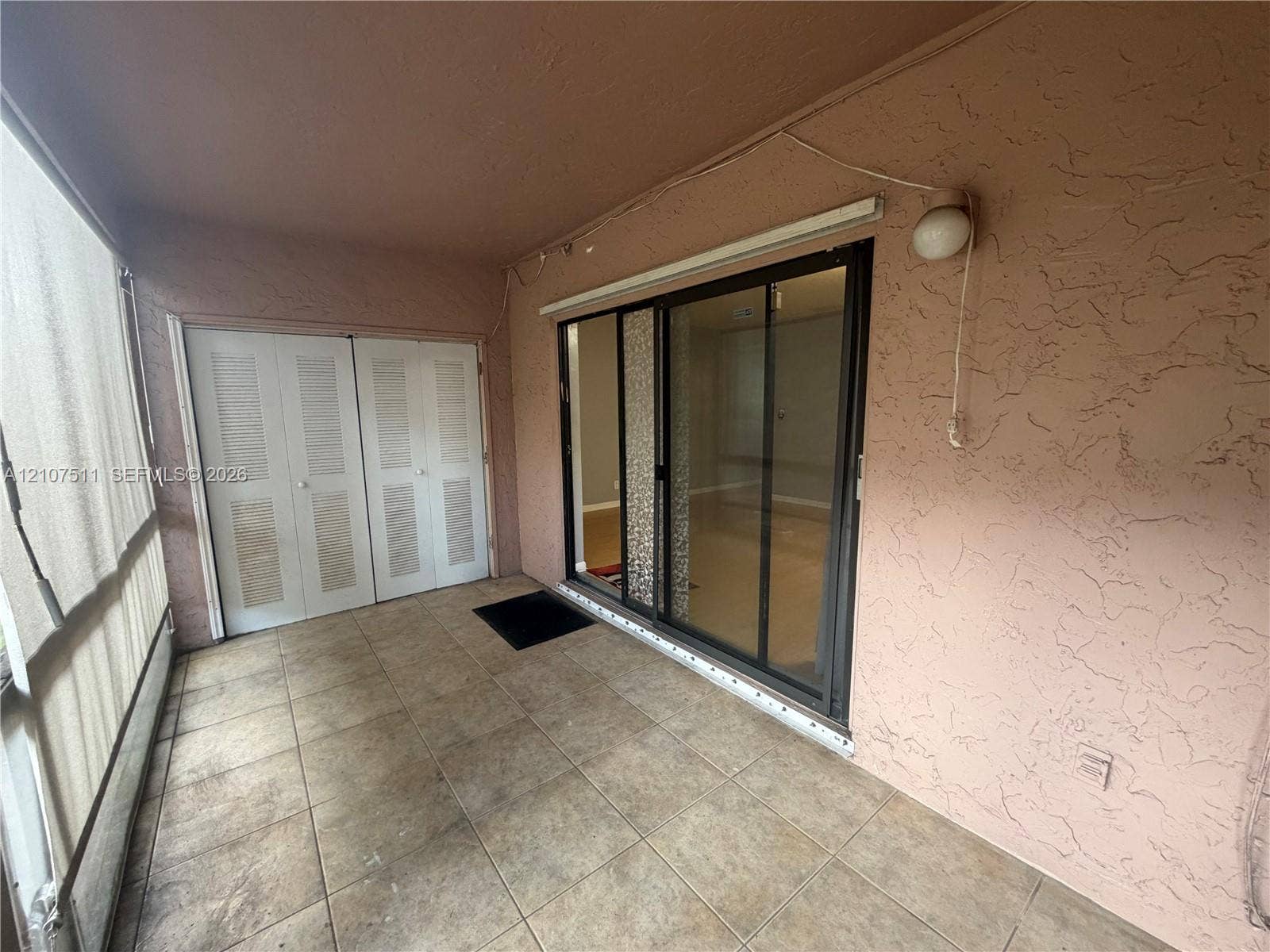 12 S Valencia Drive, #5-4, Davie, FL 33324 Covered patio featuring ceramic tile flooring, sliding glass doors, double louvered-panel closet doors, and textured stucco walls