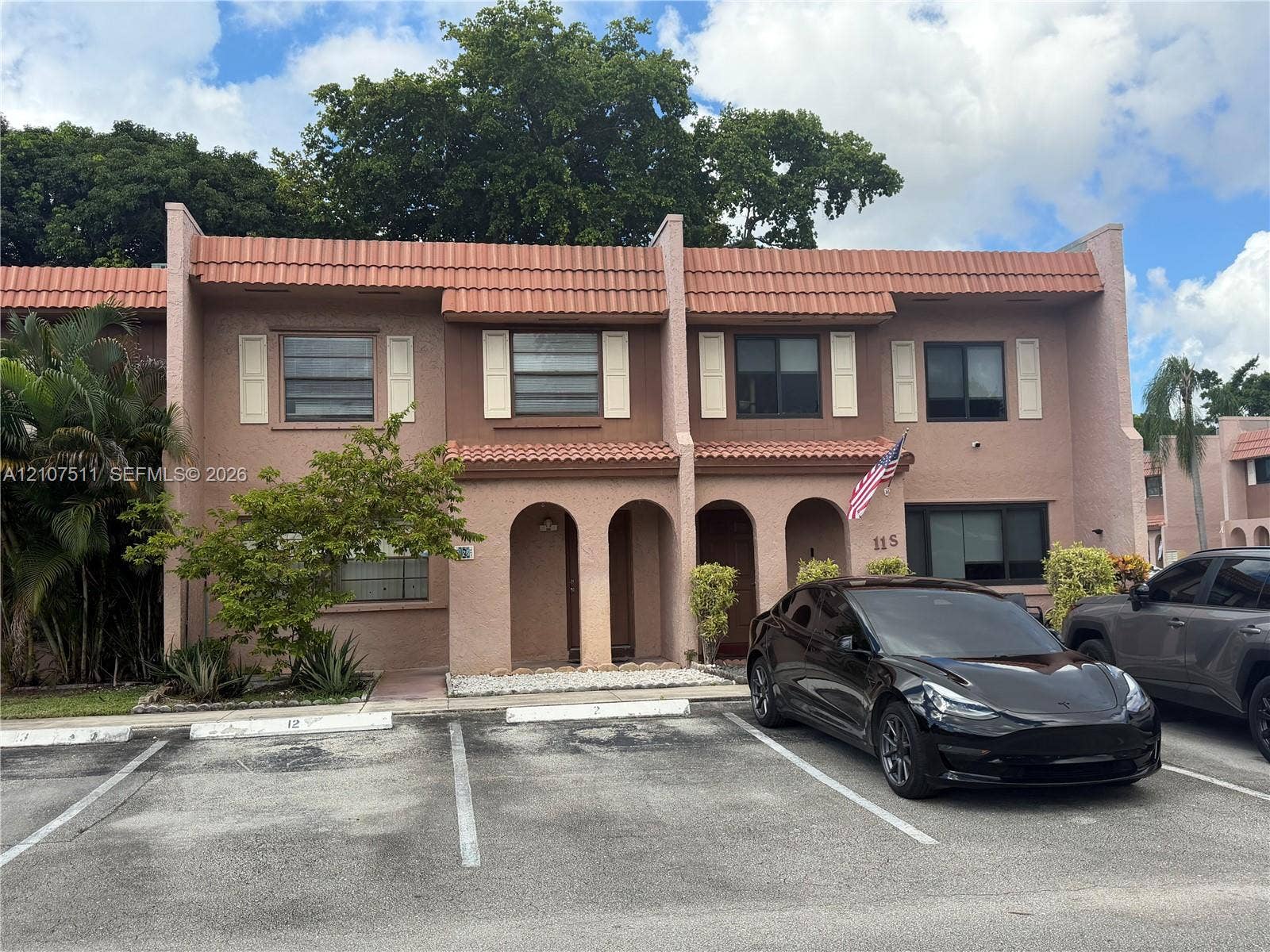 12 S Valencia Drive, #5-4, Davie, FL 33324 Two-story stucco exterior featuring arched entryway detailing, tiled roofline, and louvered shutters
