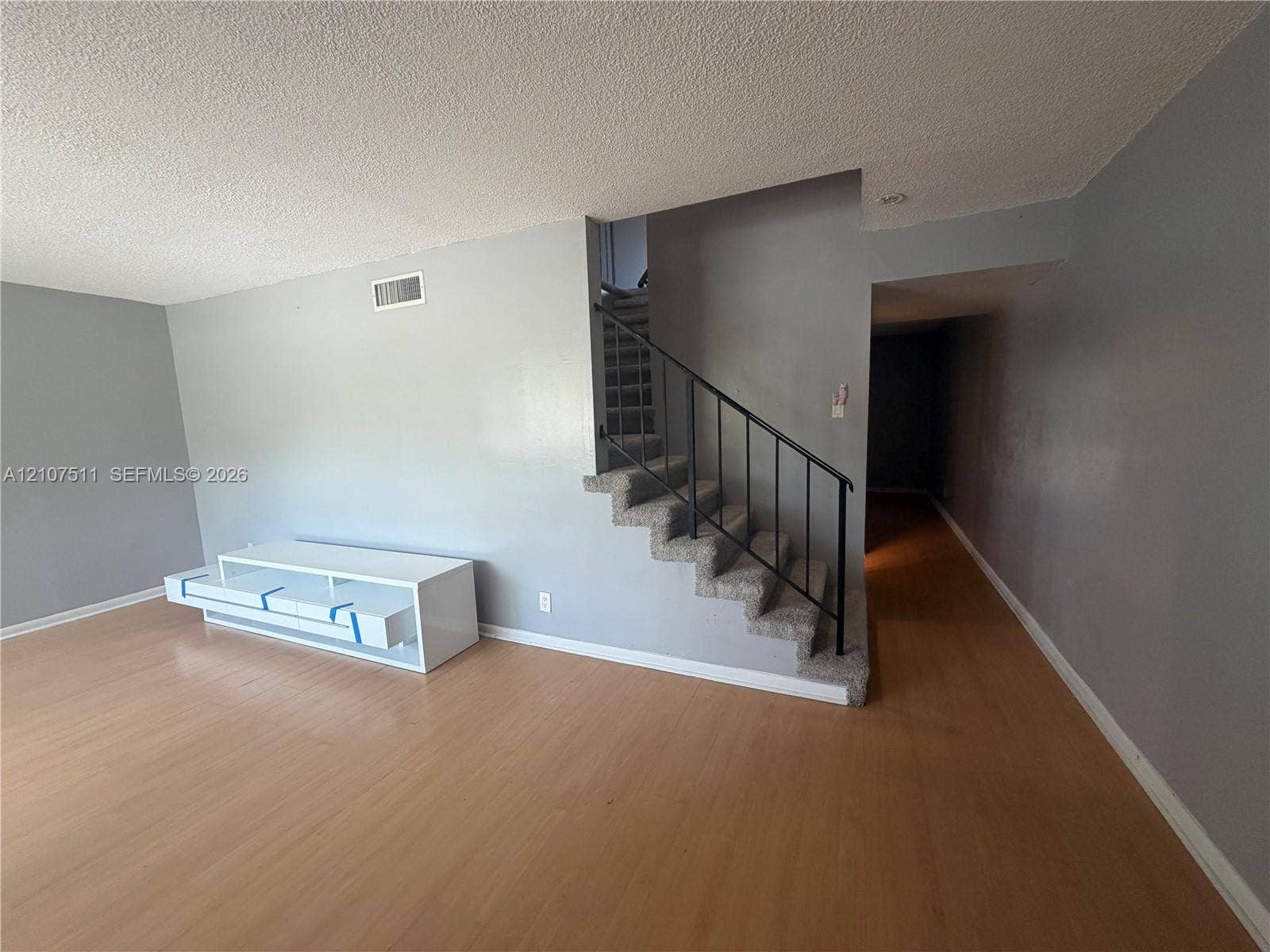 12 S Valencia Drive, #5-4, Davie, FL 33324 Open living area featuring wood-finish flooring, staircase with carpeted treads, and black metal handrailing