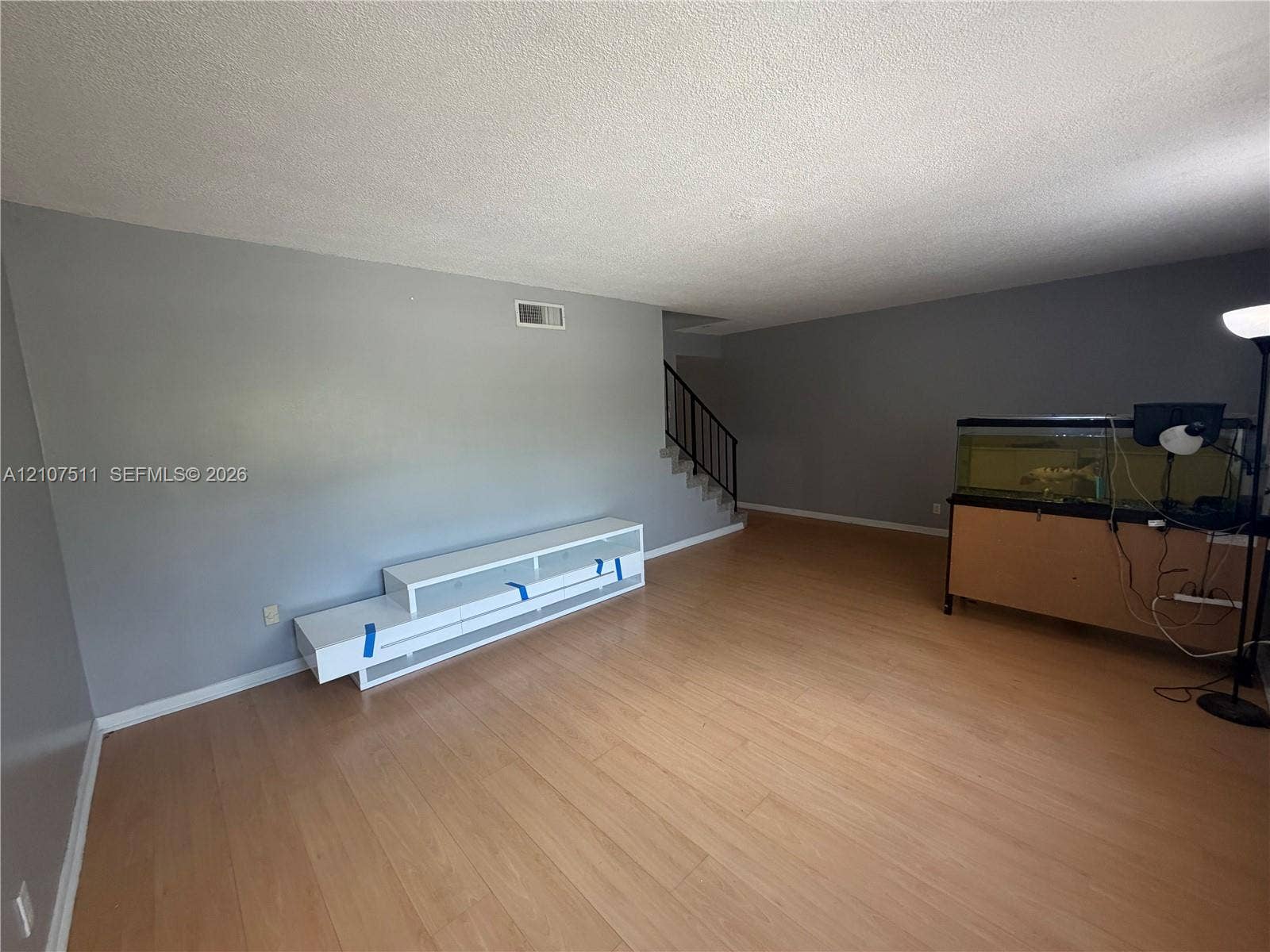 12 S Valencia Drive, #5-4, Davie, FL 33324 Open interior space featuring light-toned wood-finish flooring, neutral-toned walls, and a staircase with a black metal railing