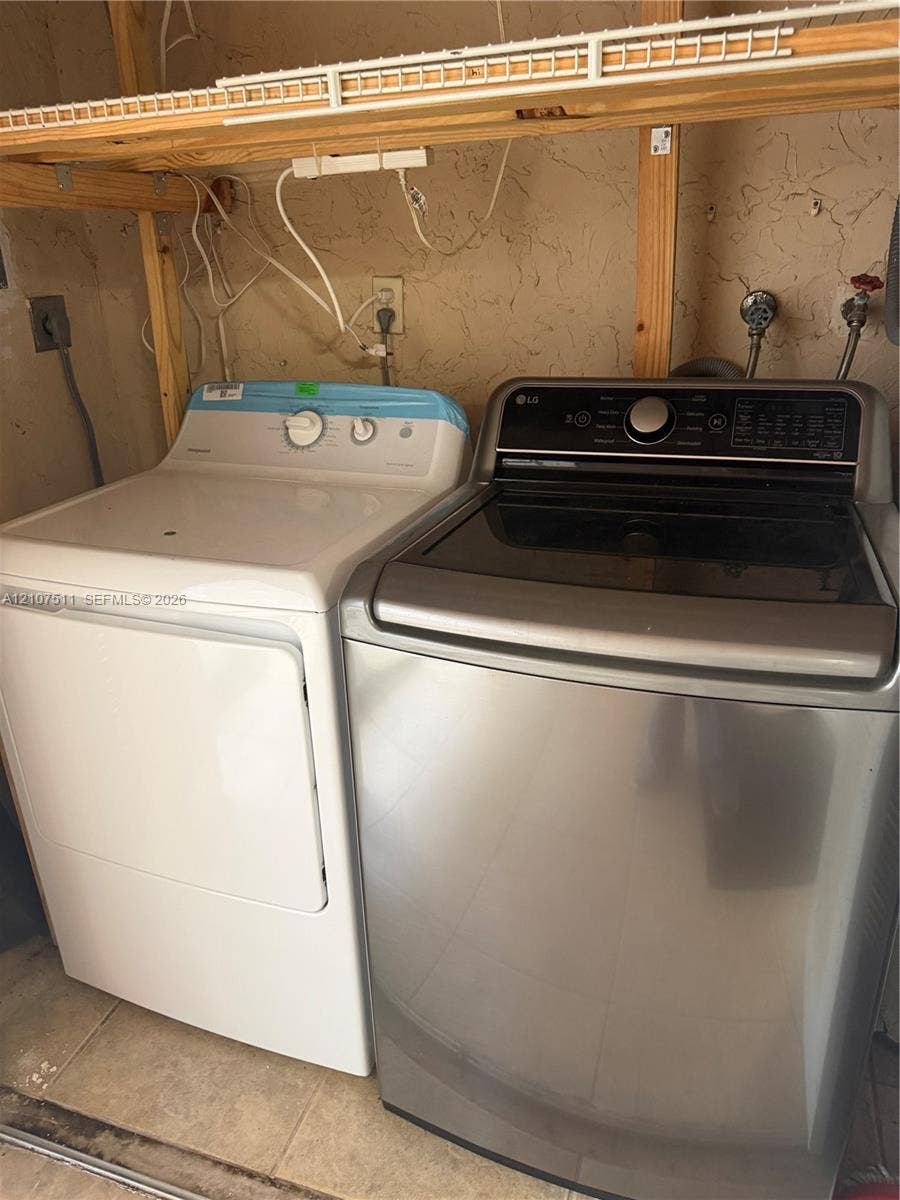 12 S Valencia Drive, #5-4, Davie, FL 33324 Laundry space featuring a stainless steel top-load washer, a high-capacity dryer, and integrated open wood shelving