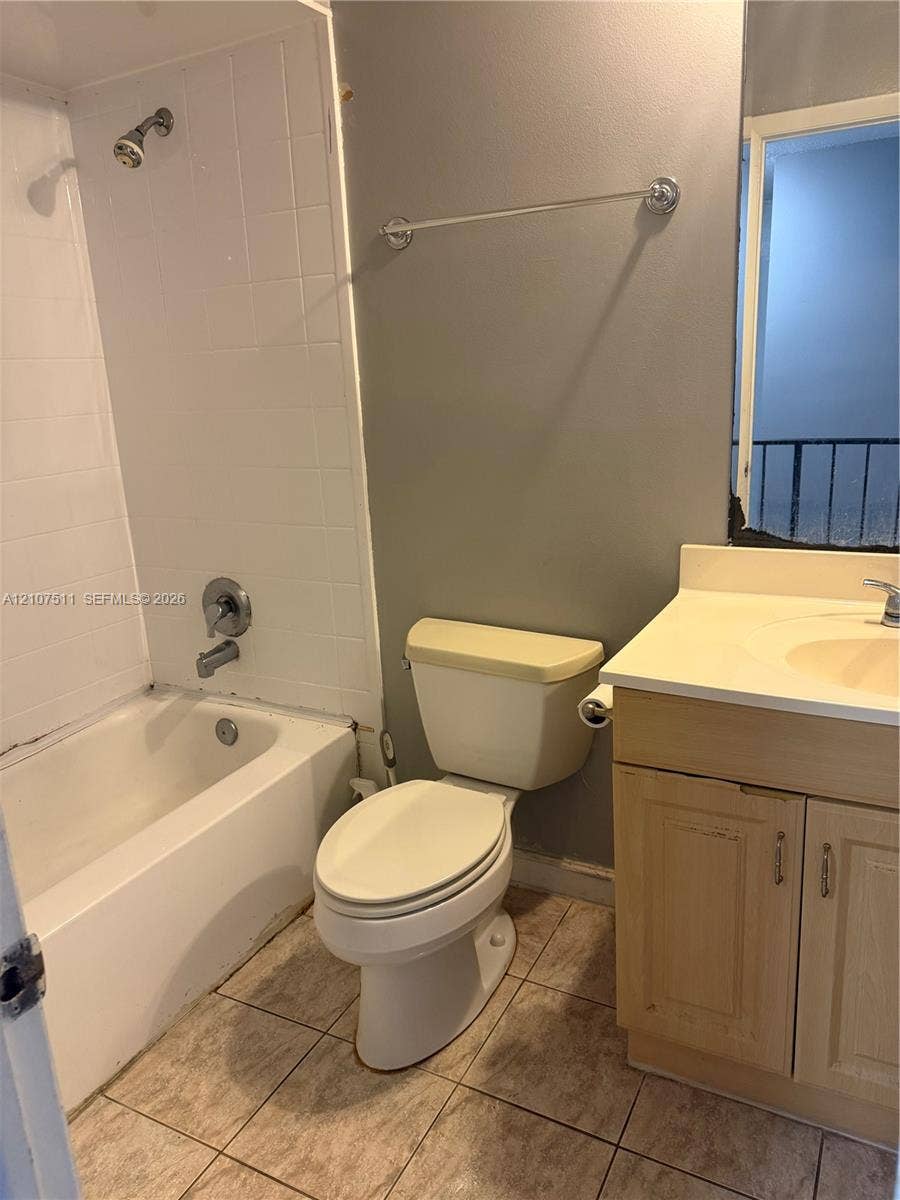 12 S Valencia Drive, #5-4, Davie, FL 33324 Bathroom featuring a built-in vanity with integrated basin, tiled tub surround, and ceramic tile flooring