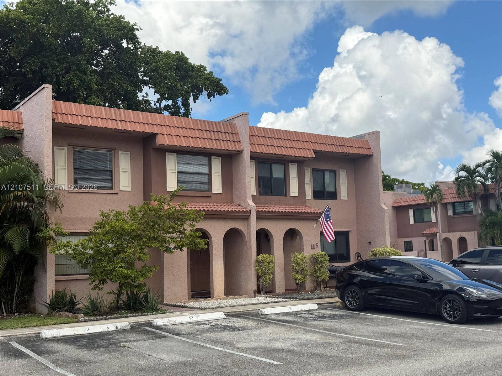 12 S Valencia Drive, #5-4, Davie, FL 33324 Two-story exterior featuring textured stucco facade, red tile roofing, arched entryways, and shuttered windows